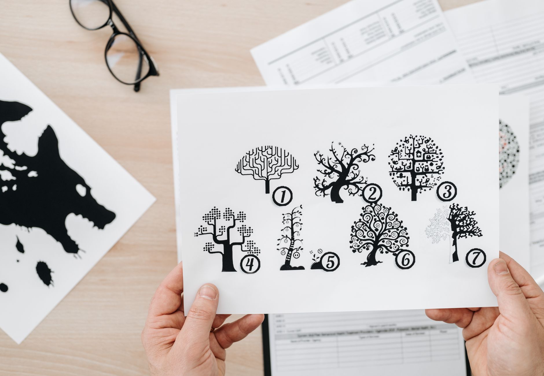 Close-up showing hands holding paper with tree test illustration for psychological assessment.