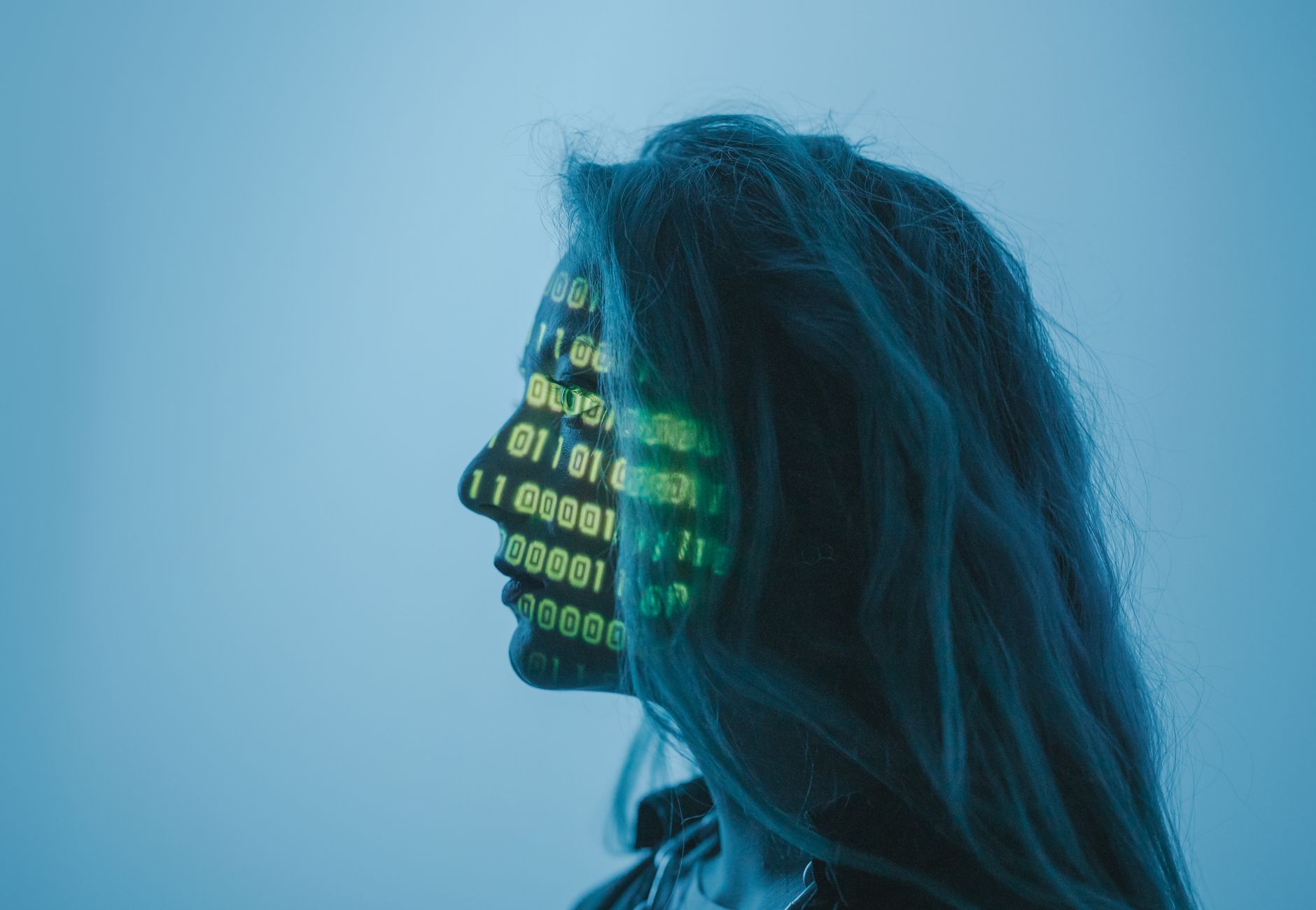Silhouette of a woman with binary code projected on her face in a digital concept setting.