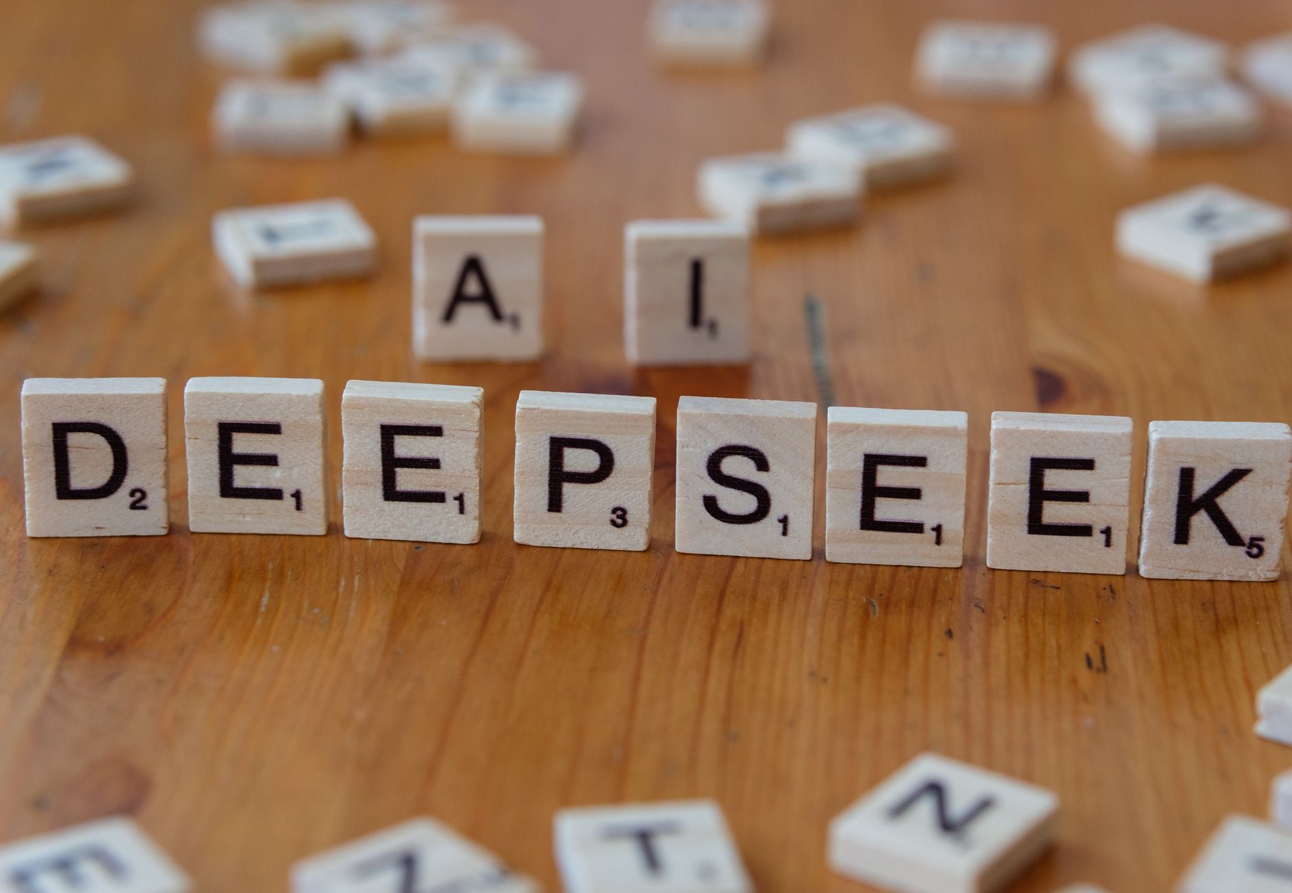 Wooden Scrabble tiles spelling 'DEEPSEEK' with 'AI' on a wooden table, illustrating AI concepts creatively.